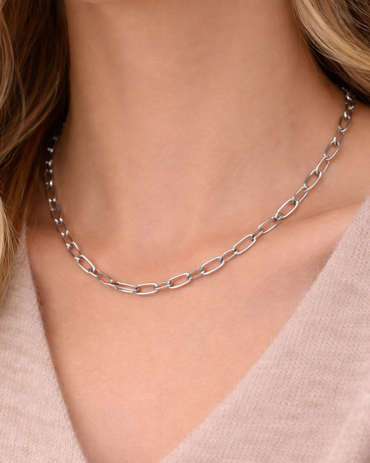 Silver chain necklace worn by a person with a neutral background