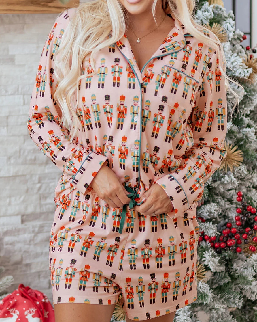 Woman wearing a festive pajama set in front of a decorated Christmas tree.