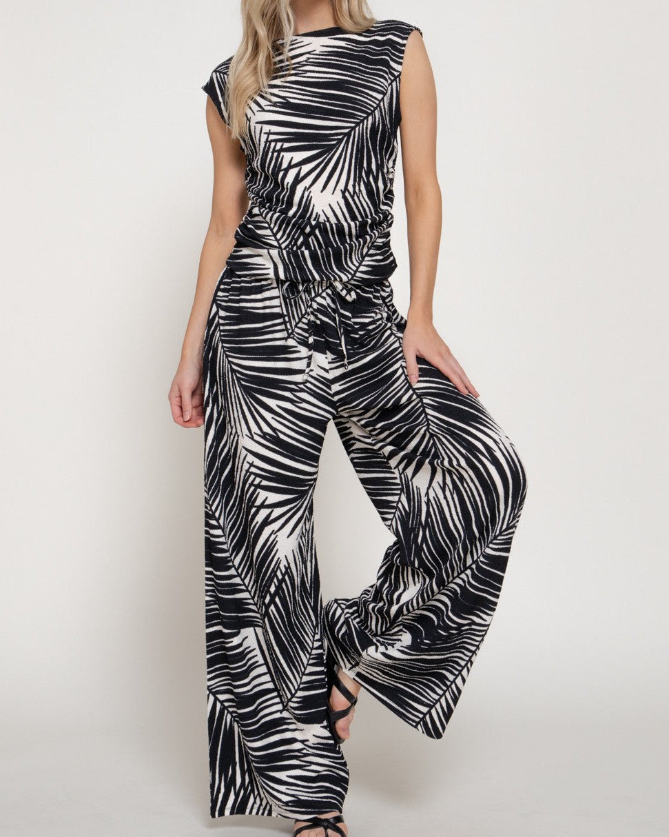 Woman wearing a black and white patterned jumpsuit on a plain background