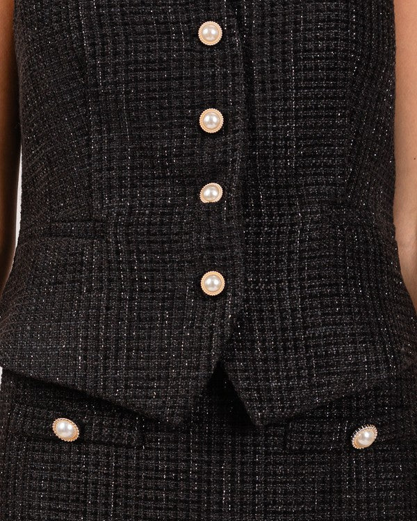 Black textured vest with pearl buttons on a plain background