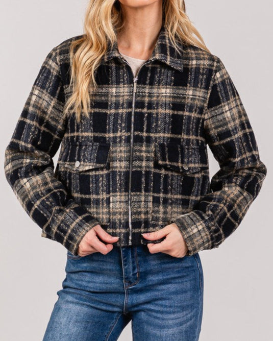 Woman wearing a plaid jacket and jeans on a plain background