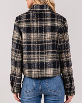 Person wearing a plaid shirt and blue jeans on a plain background