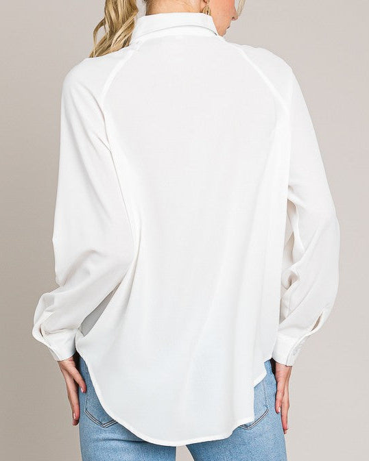 Woman wearing a white blouse and blue jeans against a beige background