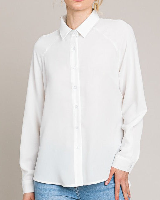 Woman wearing a white shirt and blue jeans against a neutral background