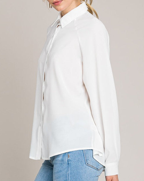 Woman wearing a white blouse and blue jeans against a plain background