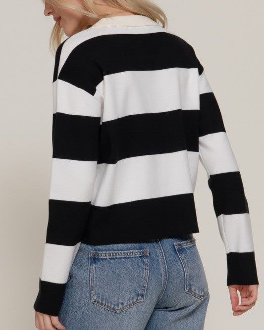 Woman wearing a black and white striped sweater with blue jeans on a plain background