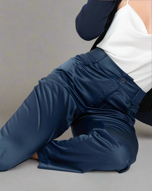 Woman wearing a navy cardigan and pants with a white top on a light background