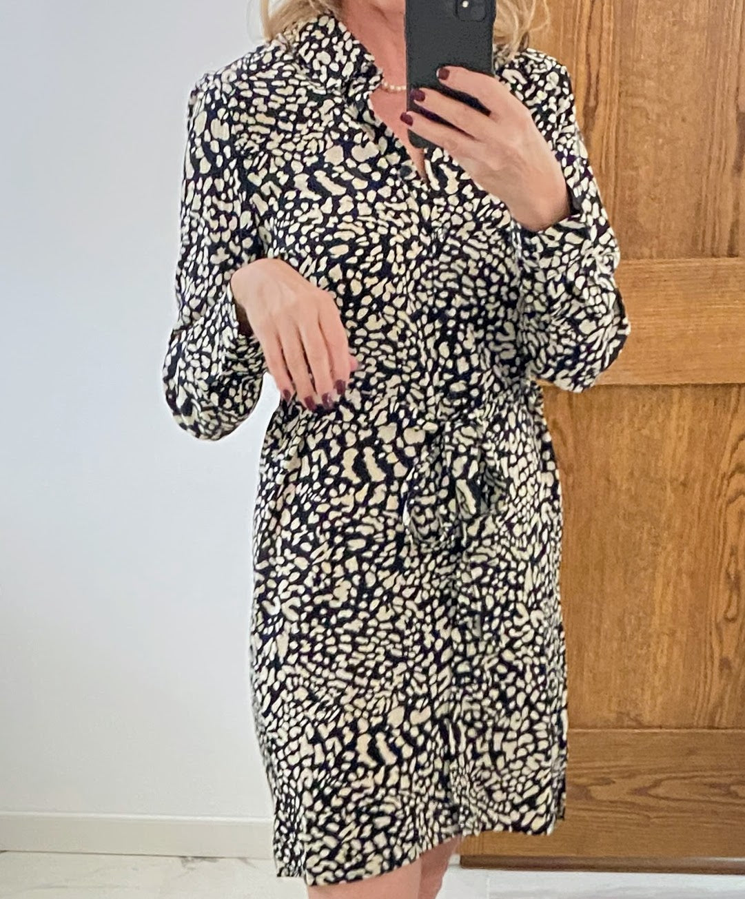 Person wearing a leopard print dress taking a mirror selfie.