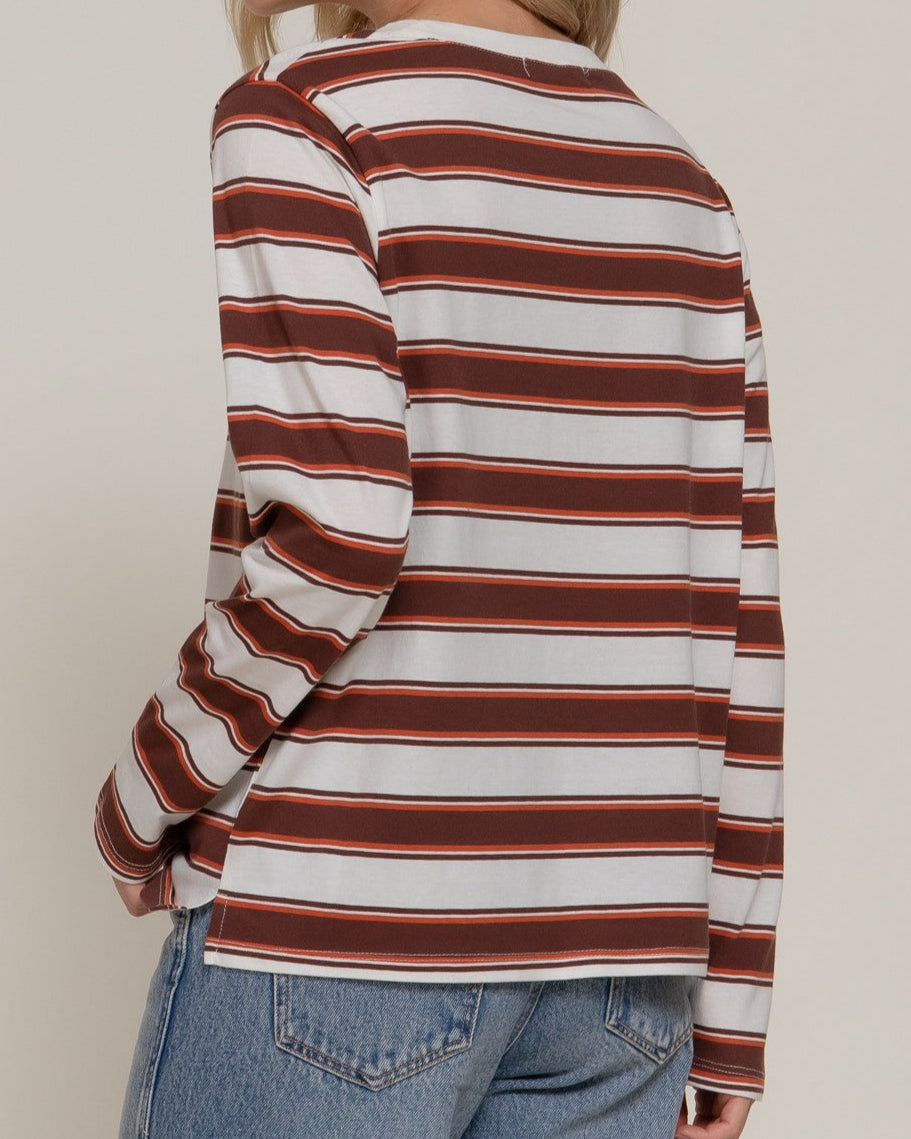 Woman wearing a striped long-sleeve top and jeans on a plain background