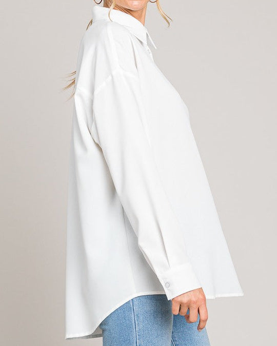 Woman wearing a white blouse and blue jeans against a plain background