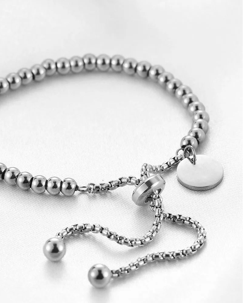 Silver beaded bracelet with a heart-shaped tag on a white background