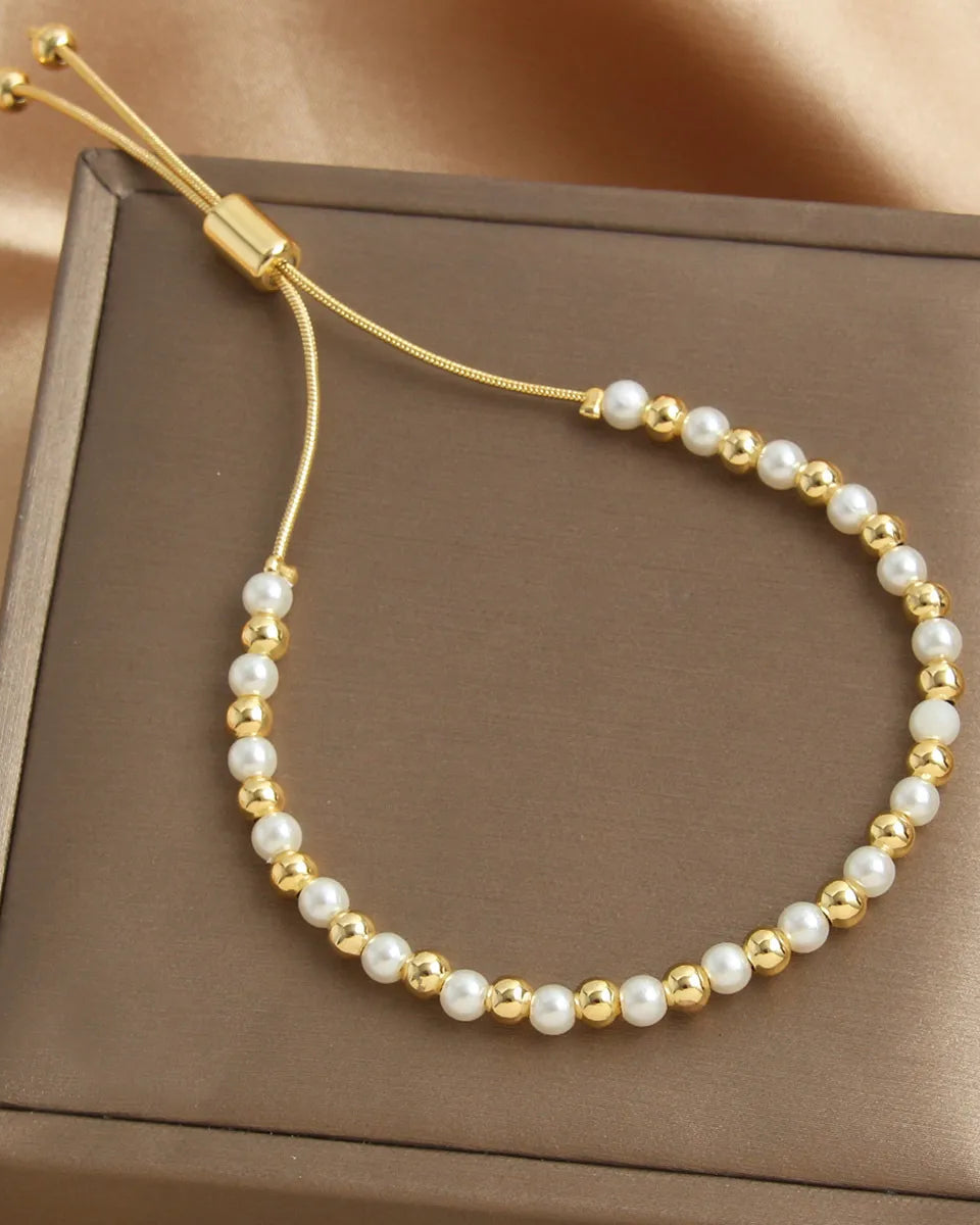 Gold and pearl bracelet on a brown box with a beige background