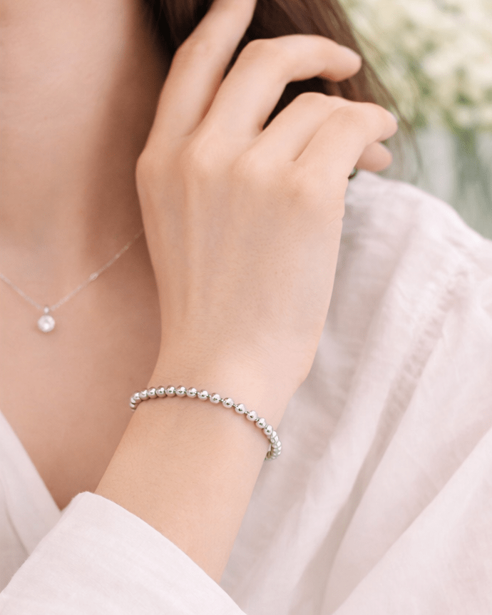 Close-up of a hand wearing a silver bracelet with a blurred background