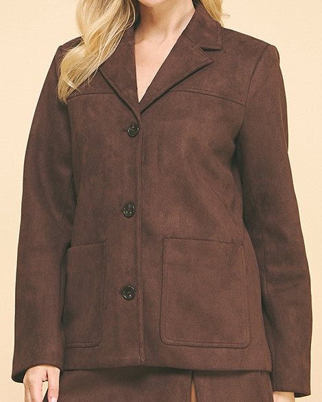 Woman wearing a brown suede jacket and skirt set on a beige background