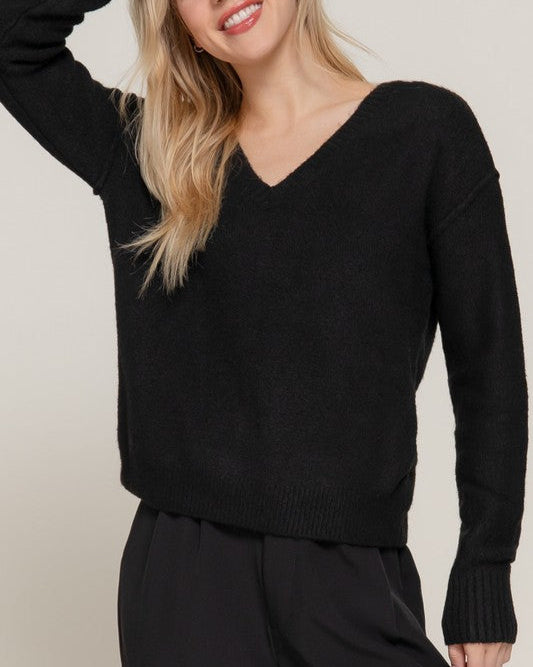 Person wearing a black sweater against a neutral background