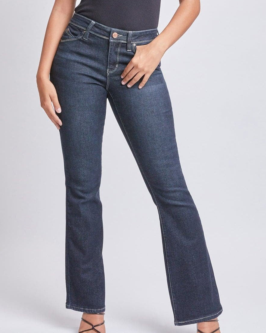 Woman wearing a black sleeveless top and blue jeans on a gray background
