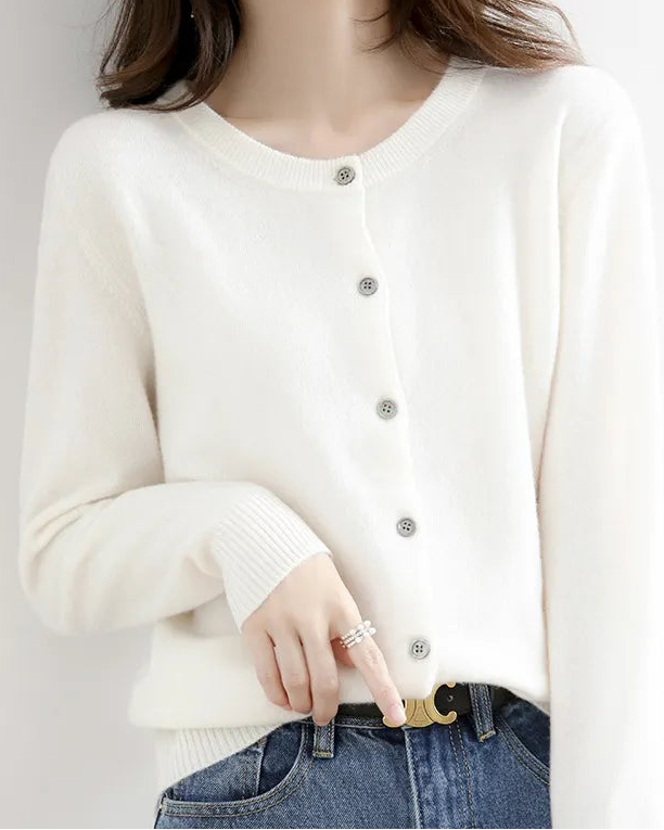 Person wearing a white cardigan over a blue denim jacket on a plain background