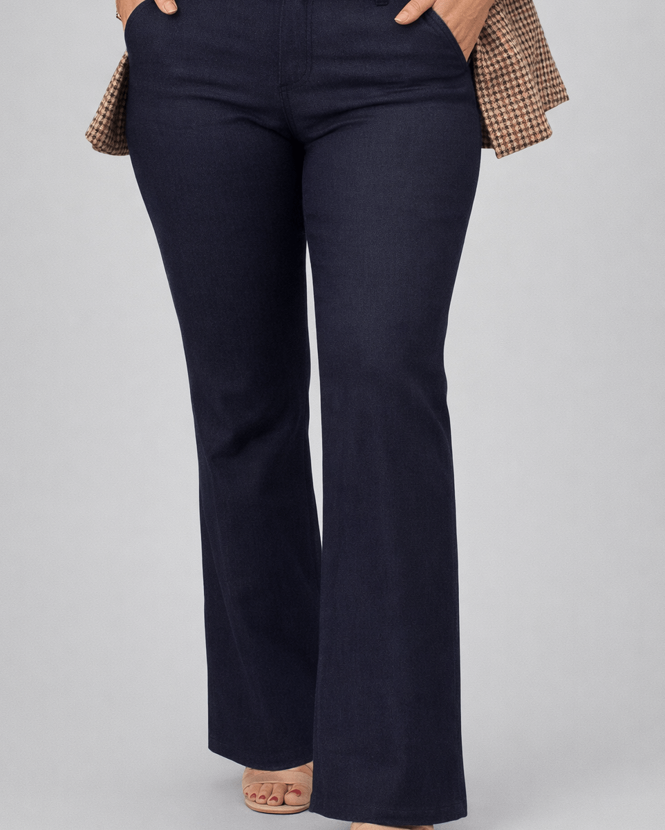 Person wearing navy flared pants with a brown blazer and beige top on a gray background