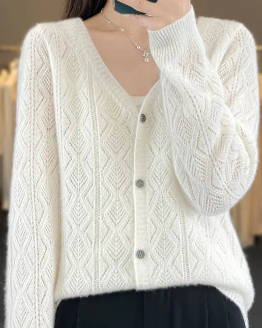 Person wearing a white cable knit cardigan in a clothing store.